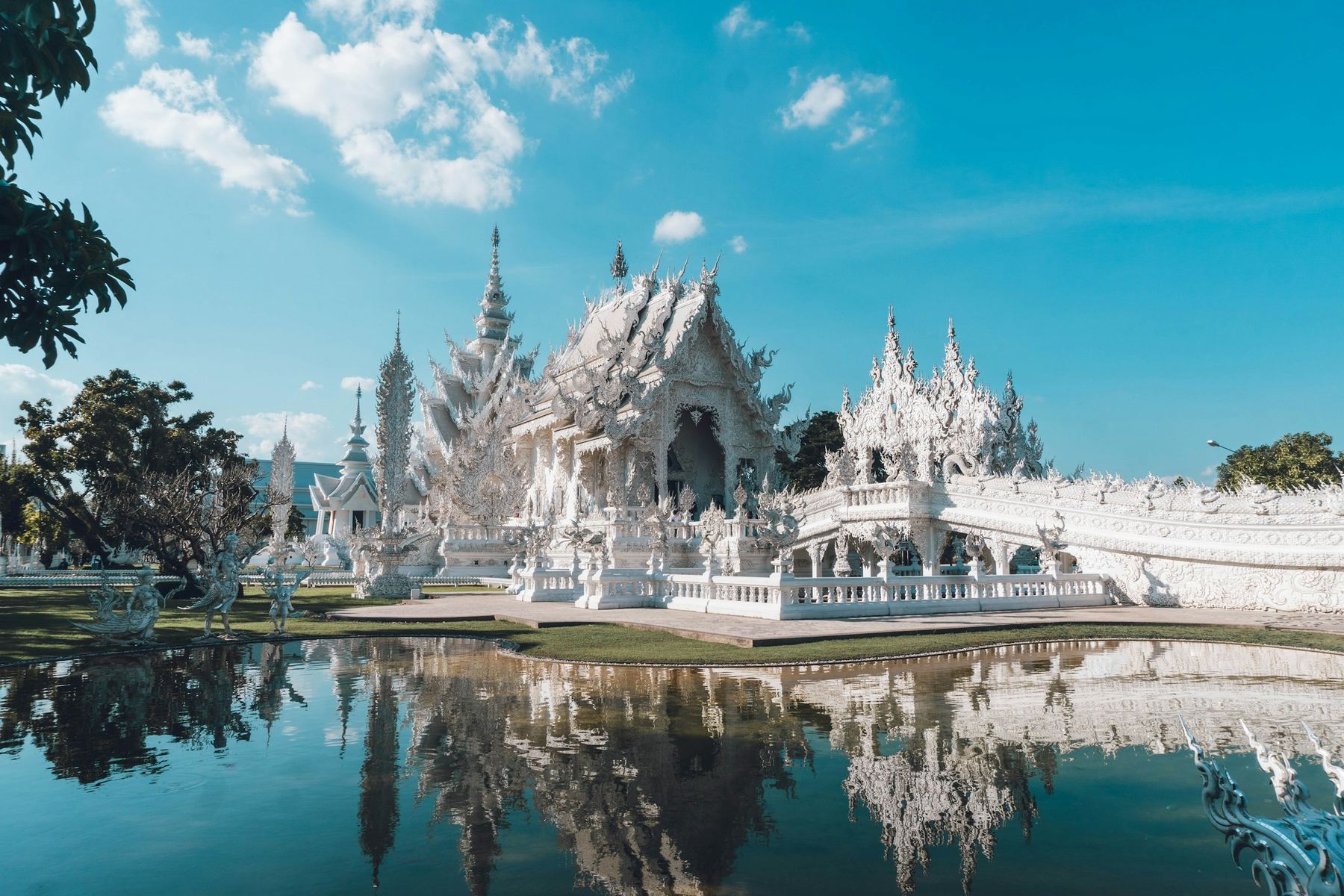 Templo Branco (Wat Rong Khun) refletido no lago em Chiang Rai, Tailândia