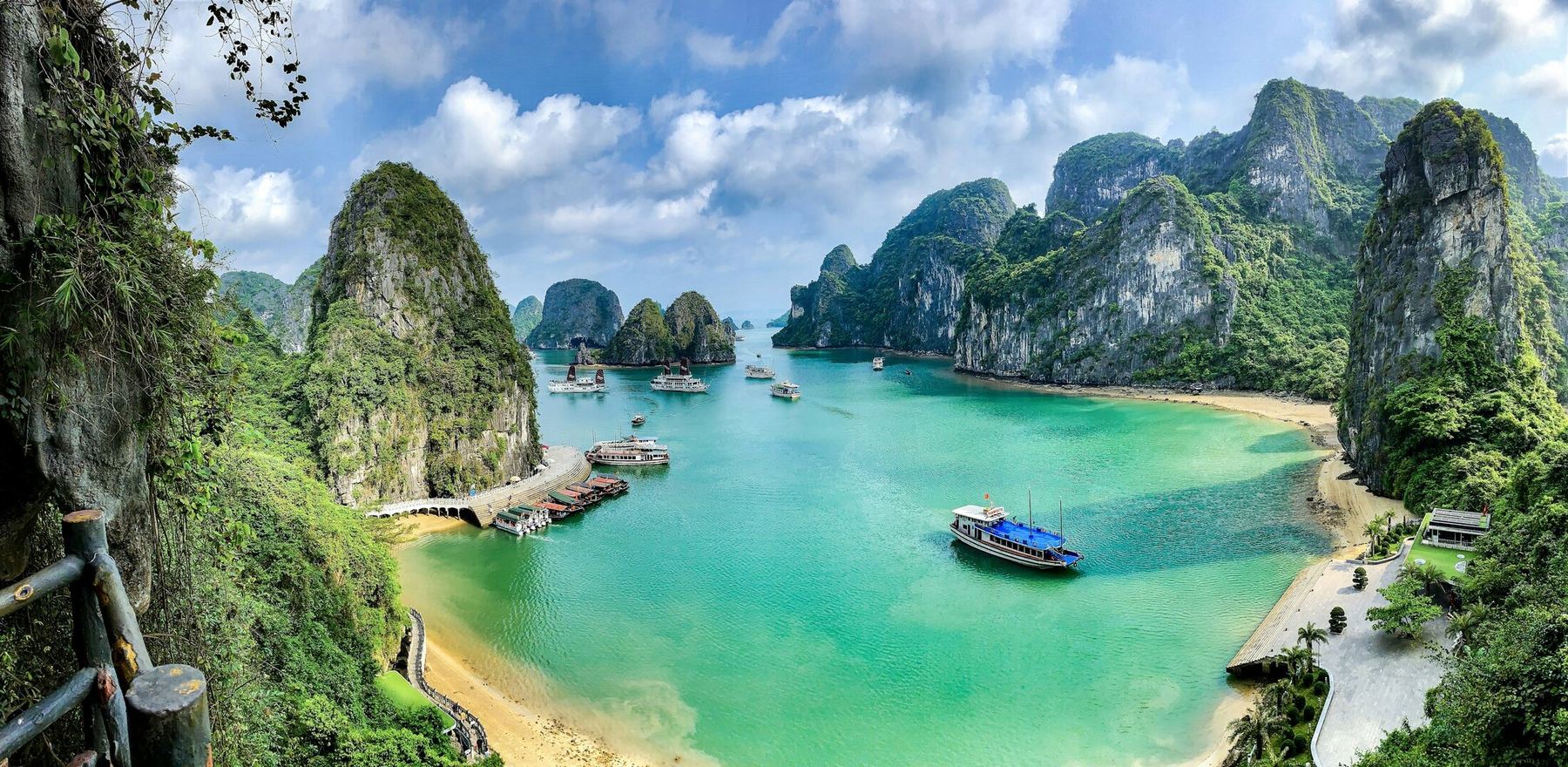 Barcos nas águas turquesa da Baía de Ha Long, entre ilhas de calcário cobertas de mata